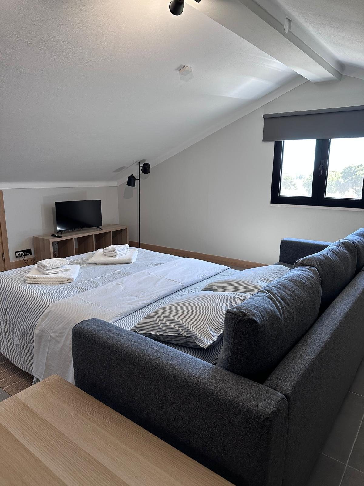 Sala do primeiro andar com sofá-cama e televisão